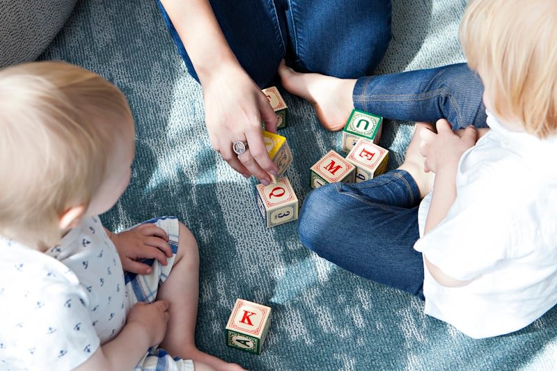 Un parent joue aux cubes en bois avec ses deux enfants